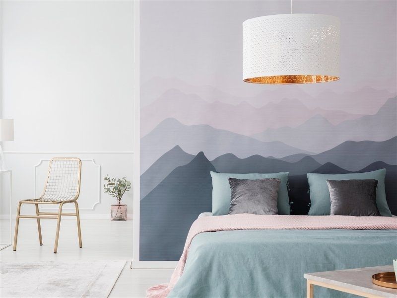 Imagem de um quarto de casal com cabeceira de adesivo com estampa de montanhas