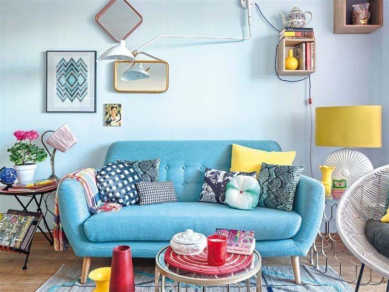 Imagem de uma sala de estar com sofás, abajures e quadros com várias cores