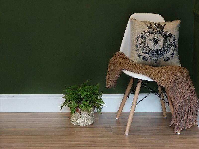 Imagem do canto de uma sala decorada com rodapé e uma cadeira próxima a parede