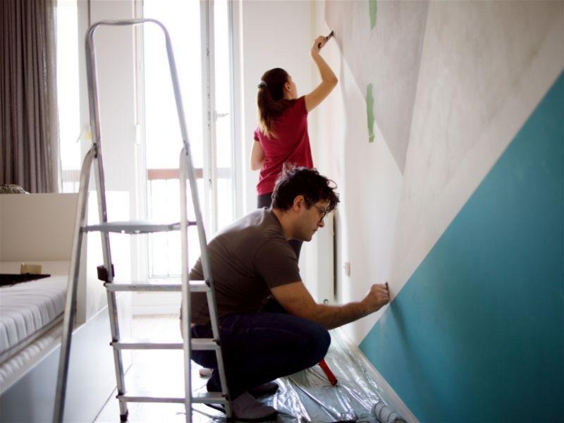 Casal pintando a parede do quarto juntos 