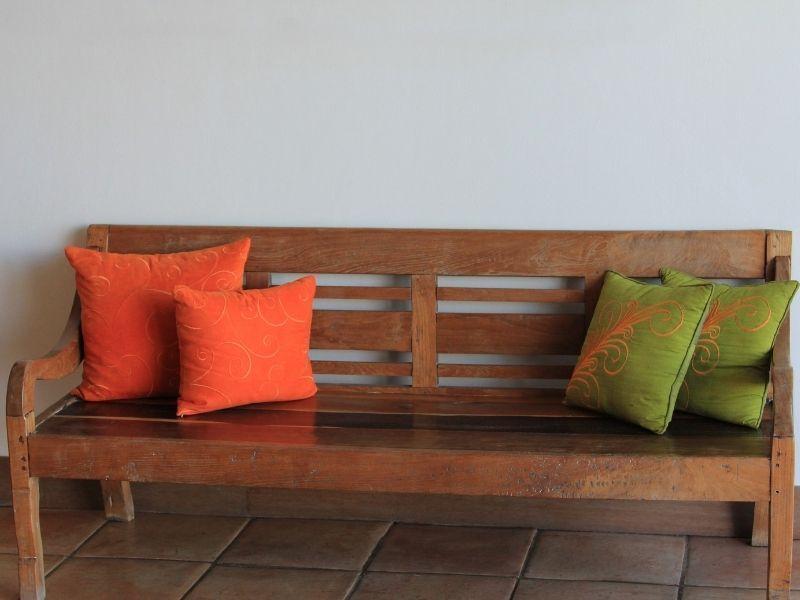 Imagem de um banco de madeira rústico com almofadas coloridas