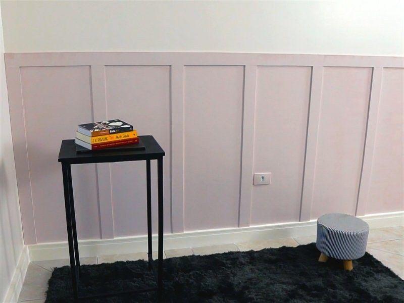 Imagem de uma sala com tapete, mesa de canto, banco e parede com cor roxo claro