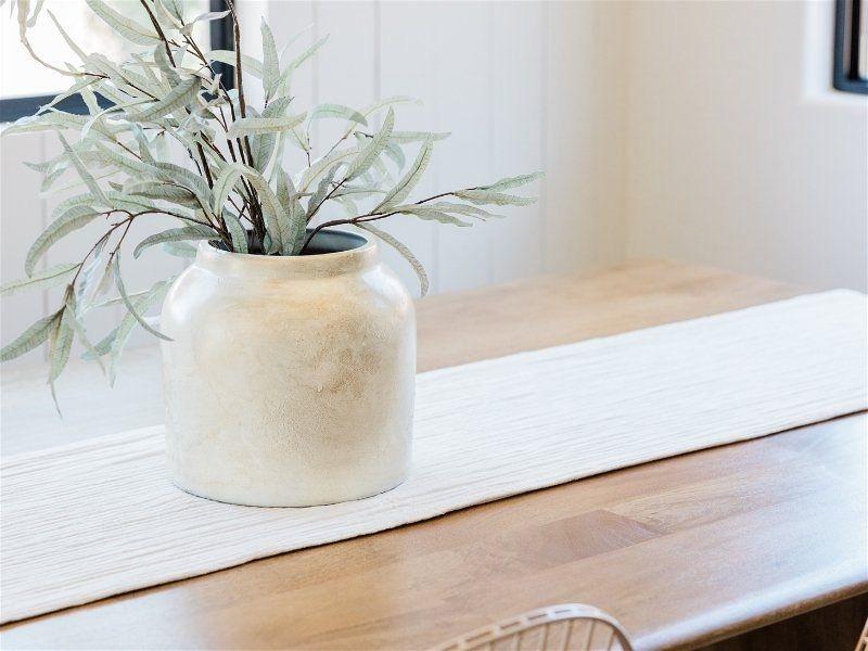 Imagem em destaque de uma mesa, contendo um vaso de planta sobre ela