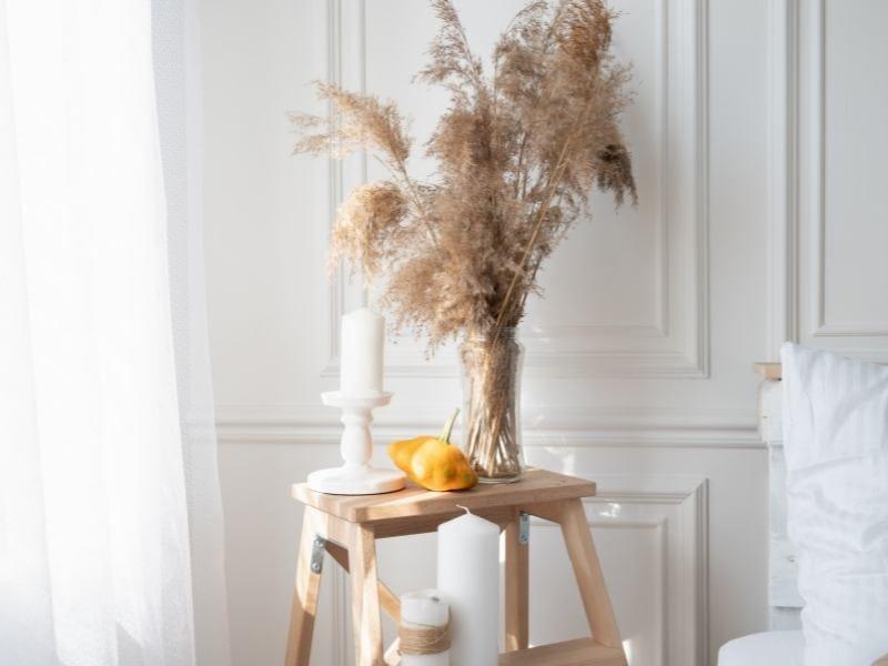 mesa lateral de madeira com vaso de plantas, vela e enfeites decorativos