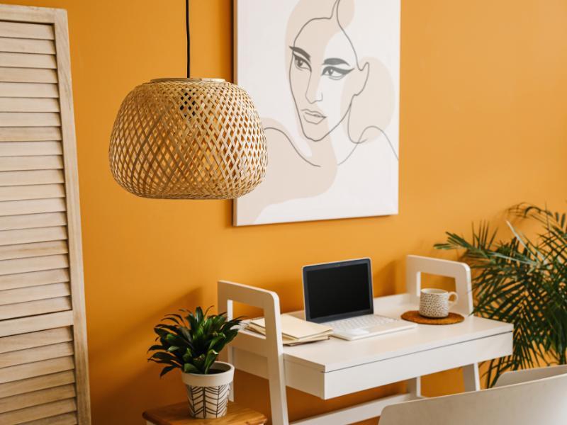 ambiente decorado com parede laranja, mesinha branca e notebook