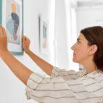 mulher ajeitando um quadro na parede