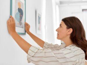 mulher ajeitando um quadro na parede