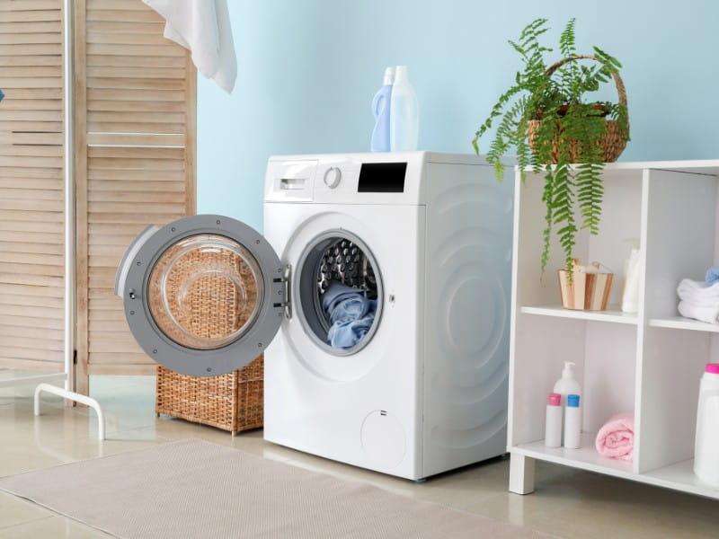 área de serviço com máquina de lavar aberta com roupas dentro