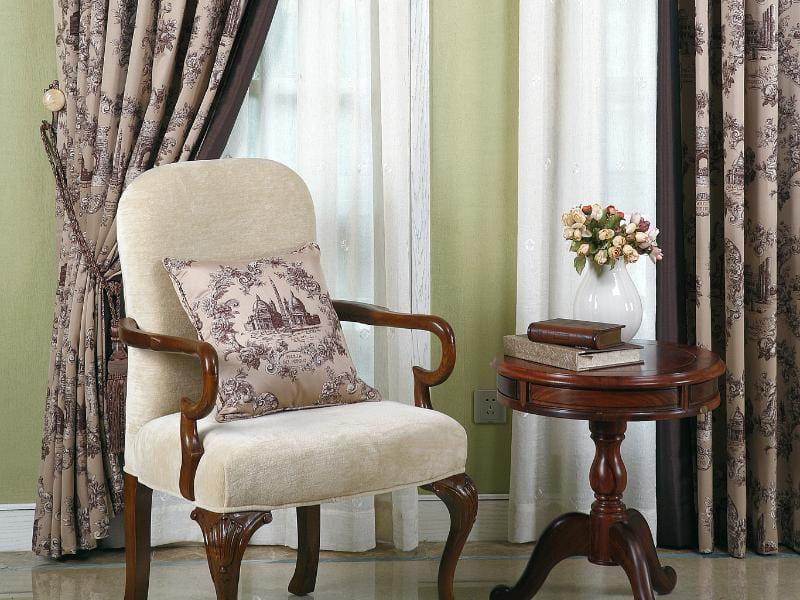 cadeira vitoriana ao lado de uma mesa lateral com vasos de flores e atrás uma cortina