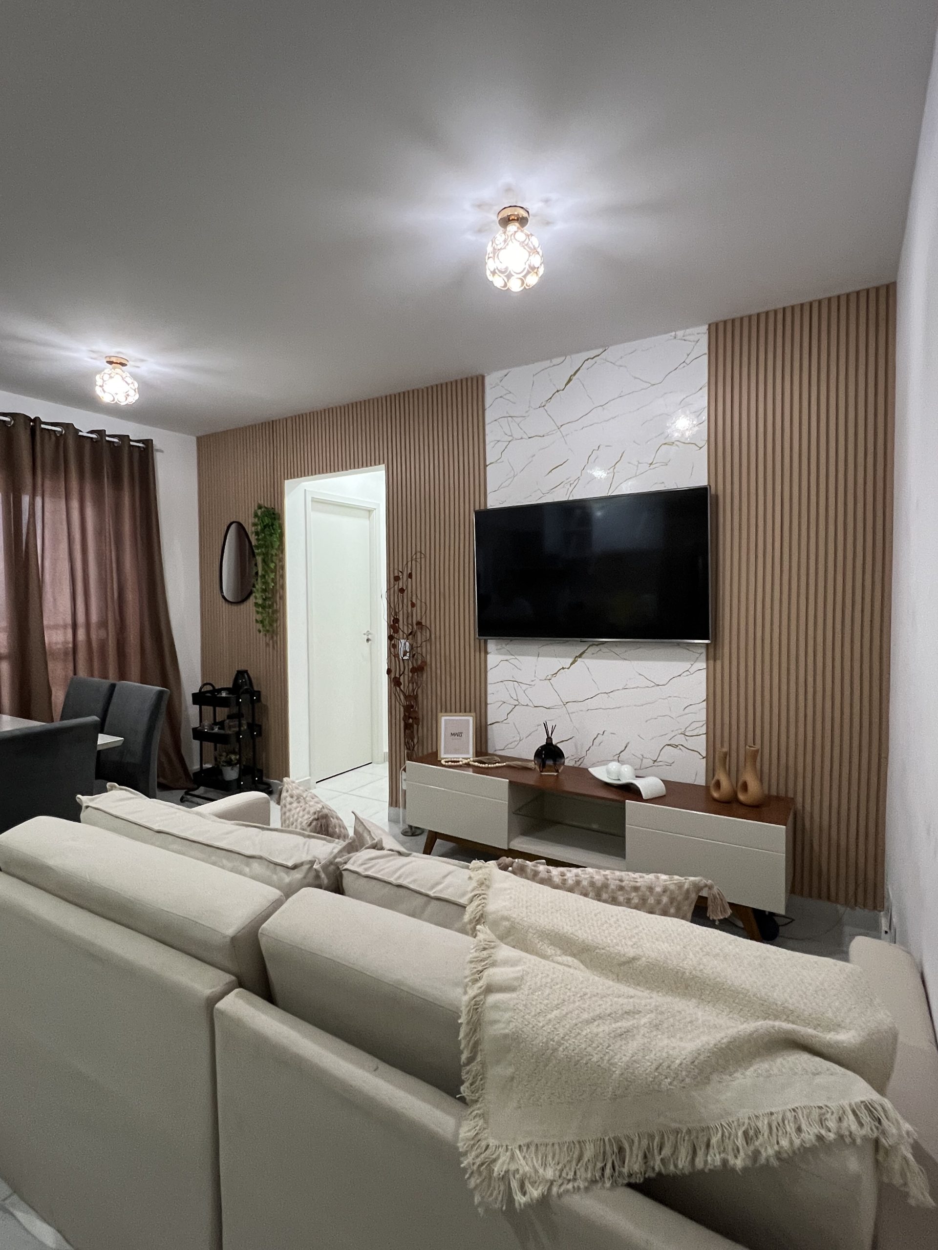 Sala de estar com painel ripado e iluminação embutida atrás da tv